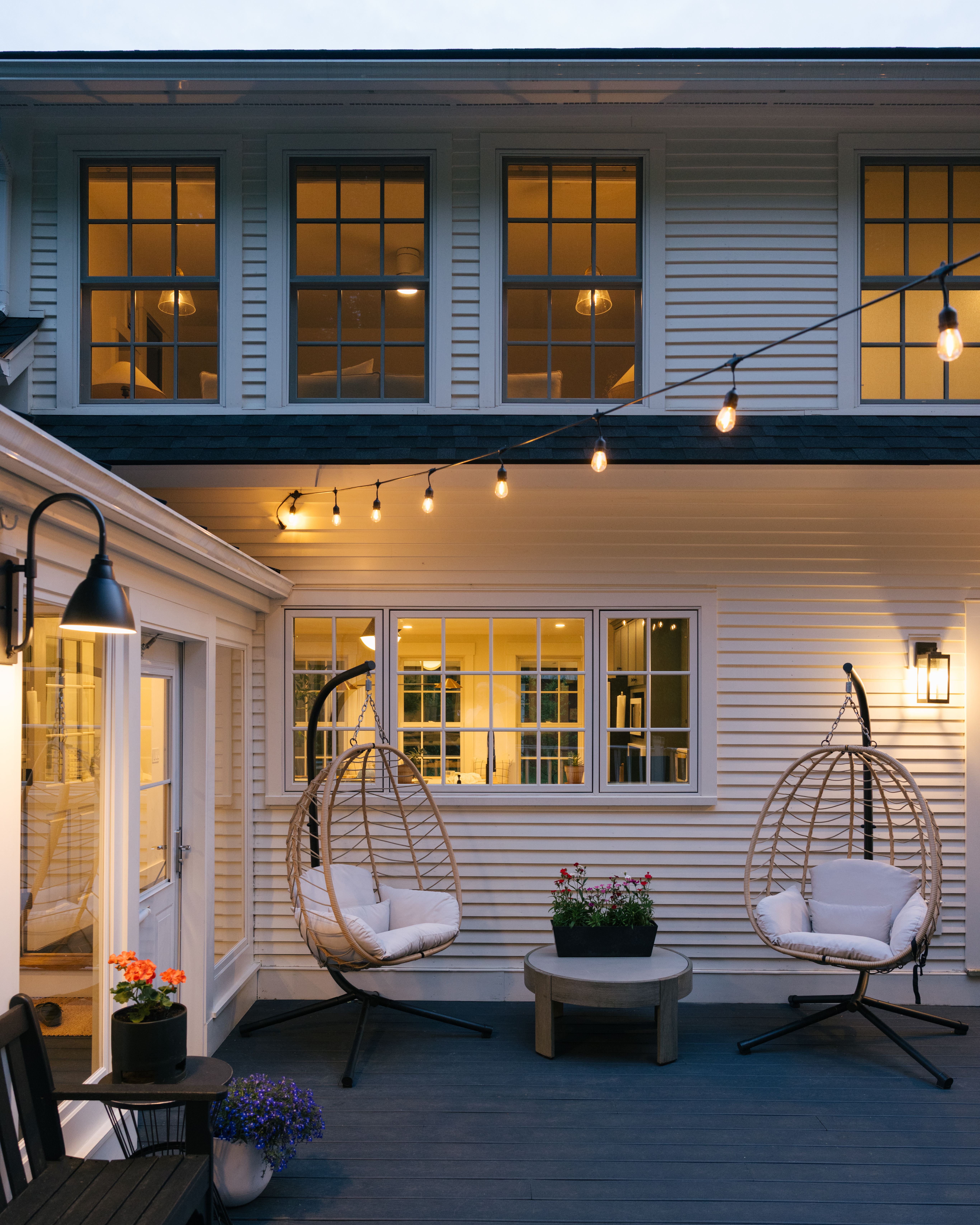 Outdoor deck with hanging egg chairs, string lights, and seating area